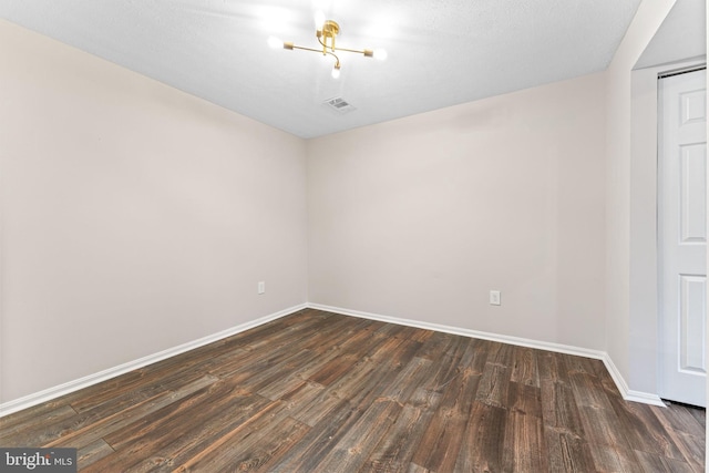 empty room featuring visible vents, baseboards, and dark wood-type flooring