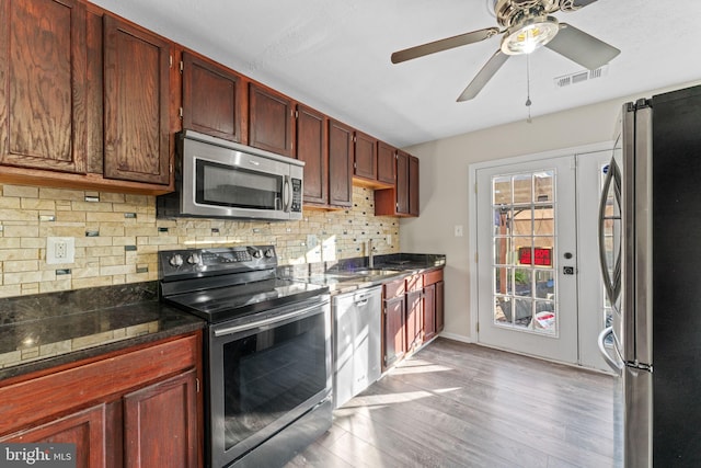 kitchen featuring visible vents, backsplash, light wood-style floors, stainless steel appliances, and a sink