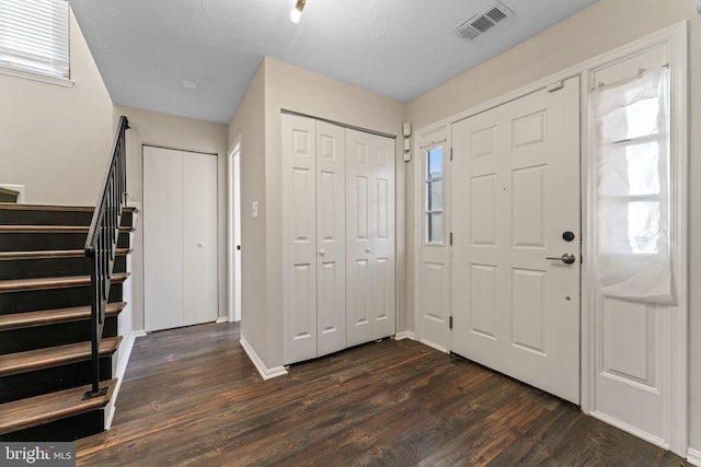 entryway featuring dark wood-style floors, visible vents, stairway, and a textured ceiling