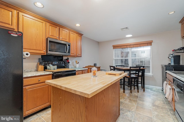 kitchen featuring visible vents, wooden counters, a center island, recessed lighting, and black appliances