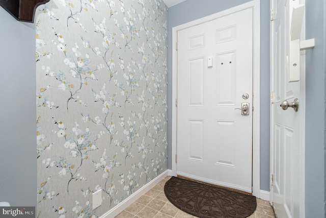 doorway with baseboards and light tile patterned flooring