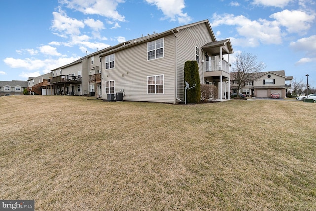 back of property with a yard, a balcony, and central AC