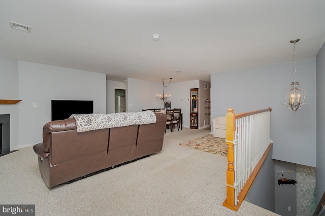 carpeted living area featuring visible vents, a fireplace with flush hearth, baseboards, and a chandelier