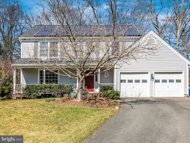 traditional-style house with a front lawn, a porch, roof with shingles, a garage, and driveway