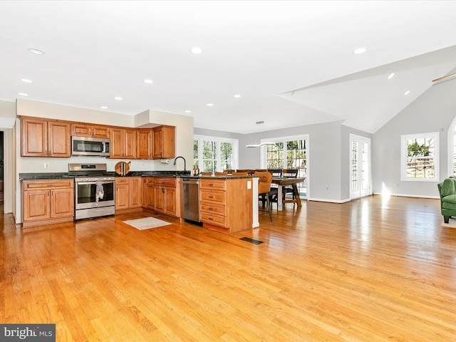 kitchen featuring light wood finished floors, a peninsula, recessed lighting, appliances with stainless steel finishes, and open floor plan