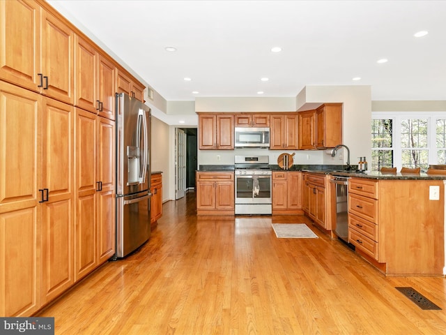 kitchen with visible vents, light wood-style flooring, recessed lighting, stainless steel appliances, and dark stone counters