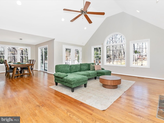 living area featuring a healthy amount of sunlight, high vaulted ceiling, and wood finished floors