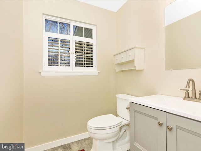 half bath with baseboards, toilet, and vanity