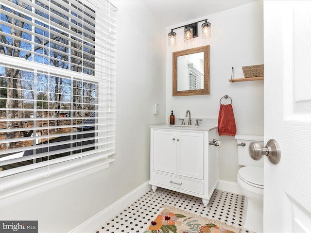 half bathroom featuring vanity, toilet, baseboards, and tile patterned flooring