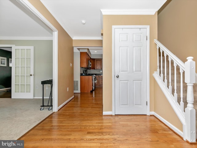 hall featuring stairway, baseboards, light wood-style floors, and ornamental molding