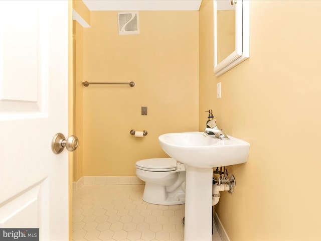 half bathroom with tile patterned floors, visible vents, toilet, and baseboards