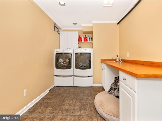 clothes washing area with baseboards, cabinet space, a sink, ornamental molding, and washer and clothes dryer