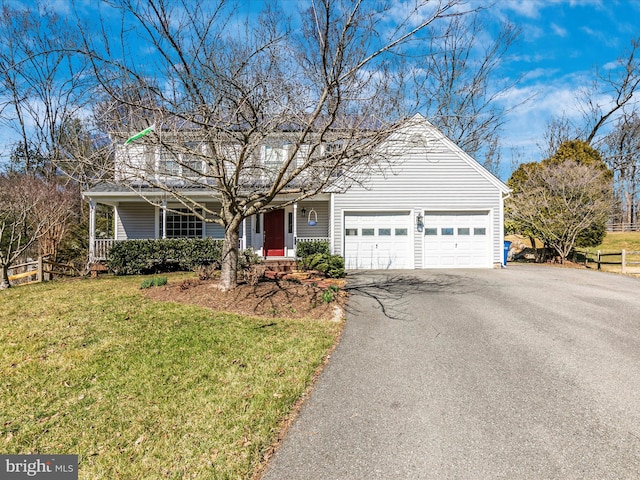 traditional home featuring aphalt driveway, a garage, covered porch, and a front lawn