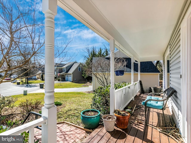 wooden deck featuring a yard, a residential view, and covered porch