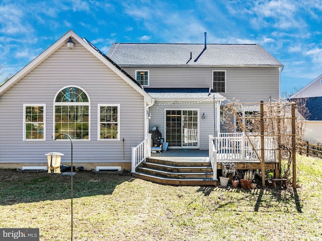 rear view of property with a deck, a yard, and roof with shingles