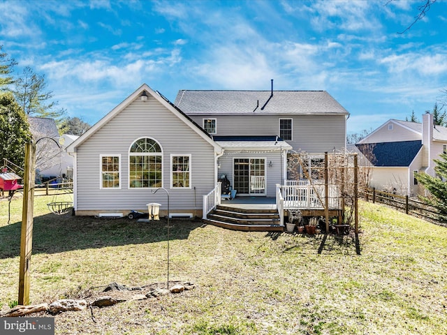 rear view of property featuring a wooden deck, a yard, and fence