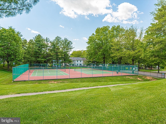 view of tennis court featuring a lawn and fence