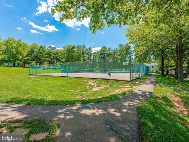 view of tennis court featuring a yard and fence