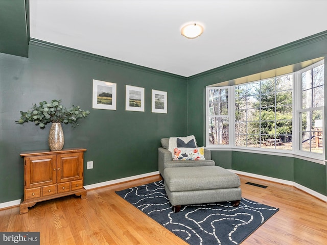 sitting room featuring visible vents, wood finished floors, and ornamental molding