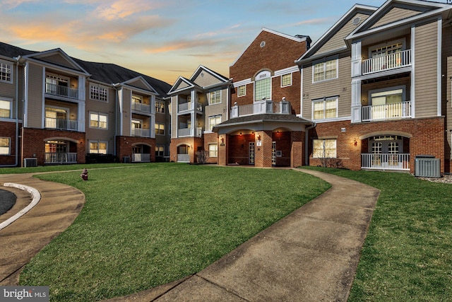 exterior space featuring a residential view, brick siding, central AC, and a front yard