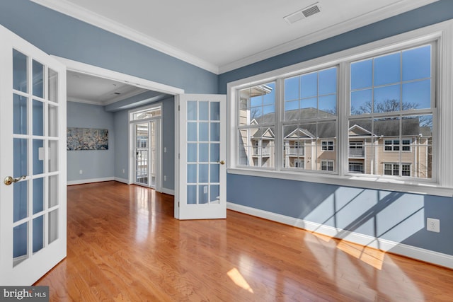 spare room featuring visible vents, ornamental molding, wood finished floors, french doors, and baseboards