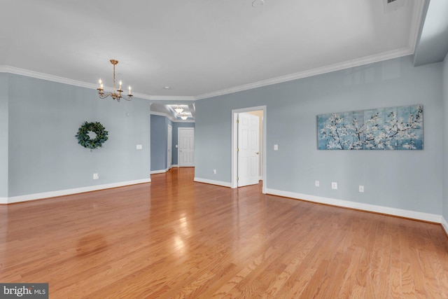 unfurnished room featuring an inviting chandelier, crown molding, baseboards, and light wood finished floors