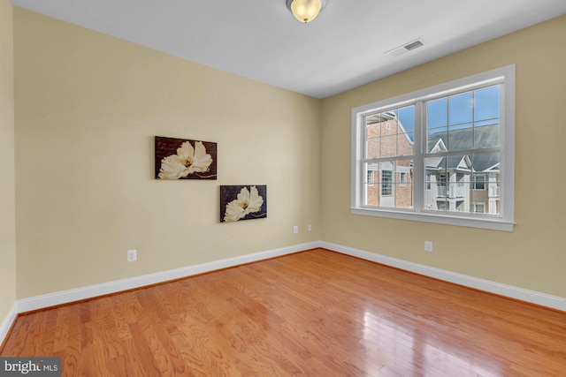 empty room with visible vents, baseboards, and wood finished floors