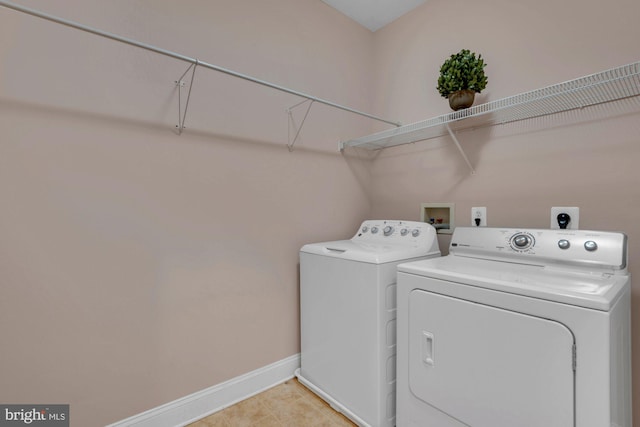 clothes washing area with baseboards, separate washer and dryer, light tile patterned flooring, and laundry area