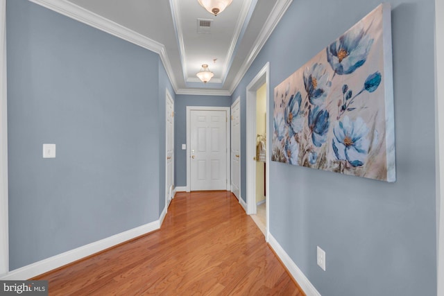 corridor with visible vents, wood finished floors, baseboards, and ornamental molding