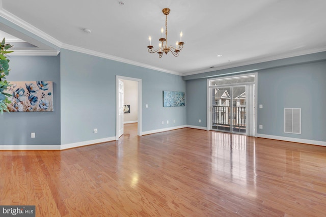 empty room featuring wood finished floors, visible vents, baseboards, an inviting chandelier, and ornamental molding