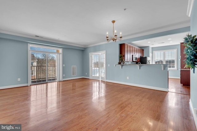 unfurnished living room featuring visible vents, baseboards, a notable chandelier, and wood finished floors