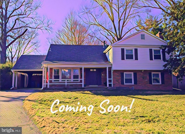 split level home featuring brick siding, an attached carport, a porch, a front yard, and driveway