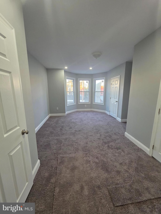 empty room with dark colored carpet, baseboards, and recessed lighting