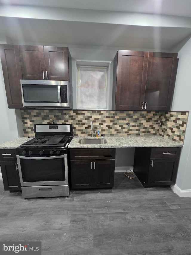 kitchen featuring a sink, decorative backsplash, light stone countertops, and stainless steel appliances