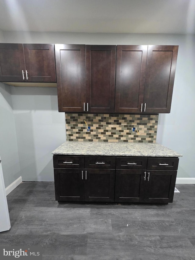 kitchen featuring light stone counters, tasteful backsplash, and dark brown cabinets