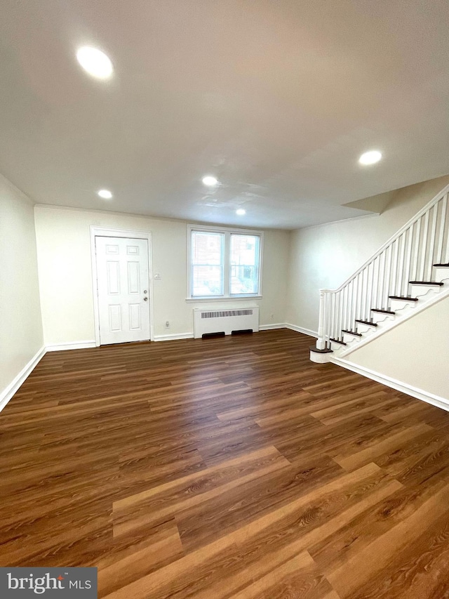 basement with stairs, radiator, wood finished floors, and baseboards