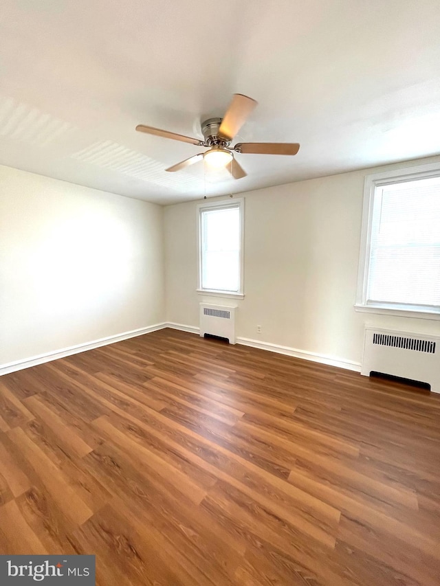 unfurnished room featuring baseboards, radiator, wood finished floors, and a ceiling fan