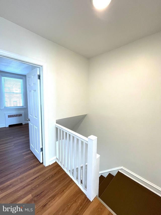 stairs featuring baseboards, radiator, and wood finished floors