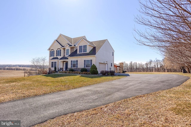 traditional-style home featuring aphalt driveway, an attached garage, and a front lawn