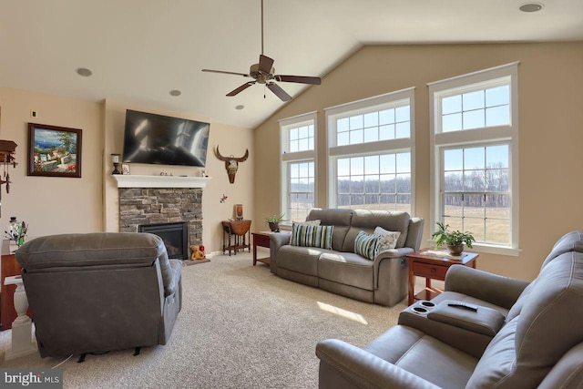 carpeted living room featuring a stone fireplace, high vaulted ceiling, and a ceiling fan