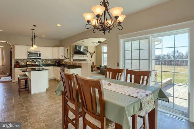 dining space with recessed lighting, visible vents, arched walkways, and ceiling fan with notable chandelier