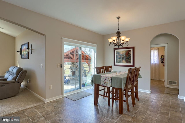 dining space featuring a notable chandelier, arched walkways, visible vents, and baseboards