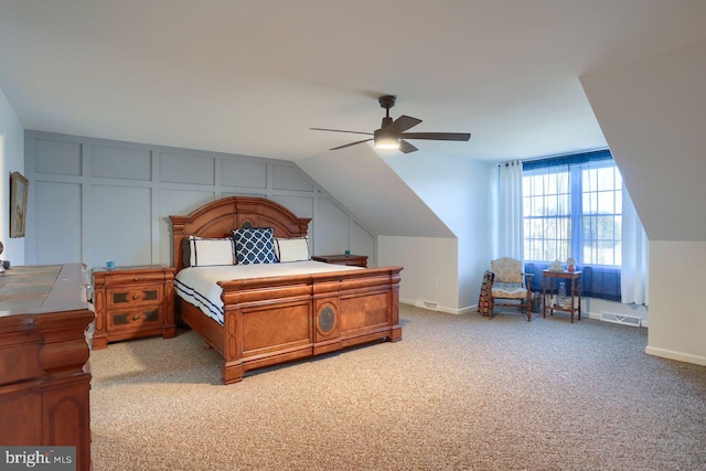 carpeted bedroom featuring visible vents, a decorative wall, baseboards, and vaulted ceiling