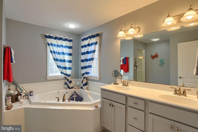 bathroom with a bath, double vanity, and a sink