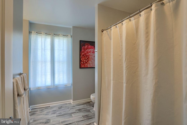 full bath with wood finish floors, baseboards, and toilet