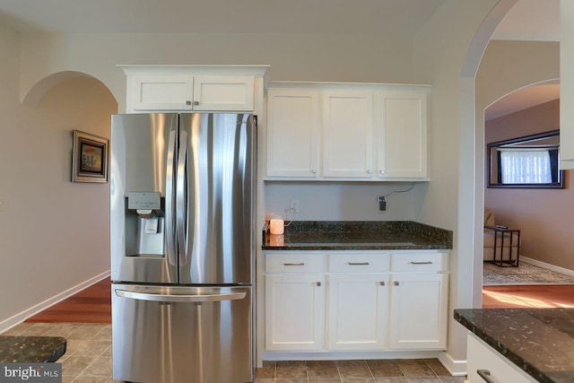 kitchen with white cabinetry, dark stone countertops, and stainless steel fridge with ice dispenser