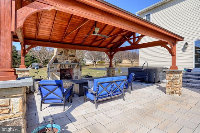 view of patio / terrace featuring a gazebo, a ceiling fan, and an outdoor stone fireplace