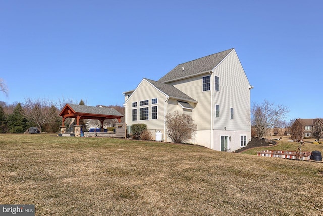 back of property featuring a gazebo and a lawn