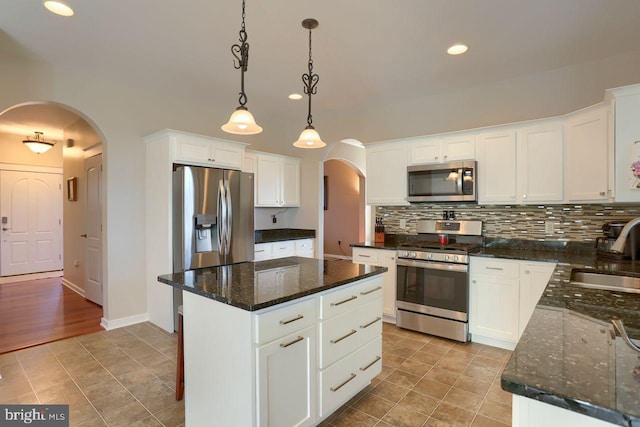 kitchen featuring a sink, decorative backsplash, arched walkways, and stainless steel appliances