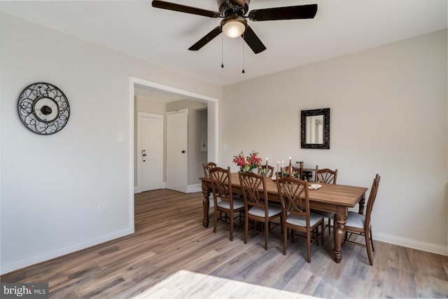 dining space with baseboards, wood finished floors, and a ceiling fan